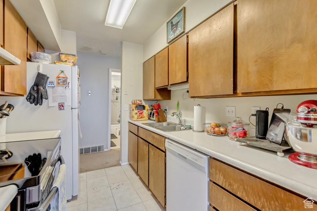 Kitchen featuring white dishwasher, stainless steel electric range, light tile patterned floors, and sink