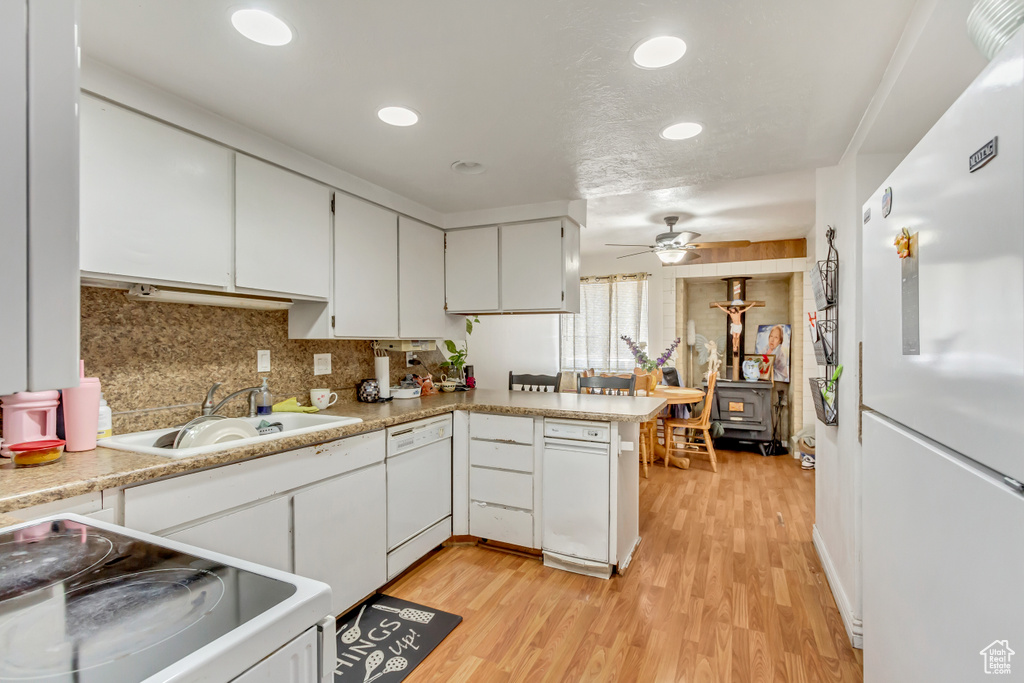 Kitchen featuring ceiling fan, white cabinets, kitchen peninsula, sink, and white appliances