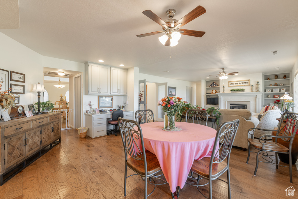 Dining space featuring built in shelves, light hardwood / wood-style floors, and ceiling fan