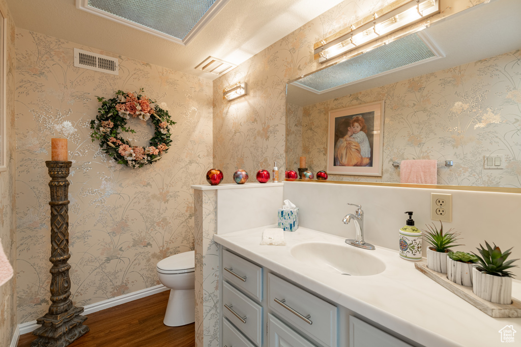 Bathroom with wood-type flooring, vanity, and toilet