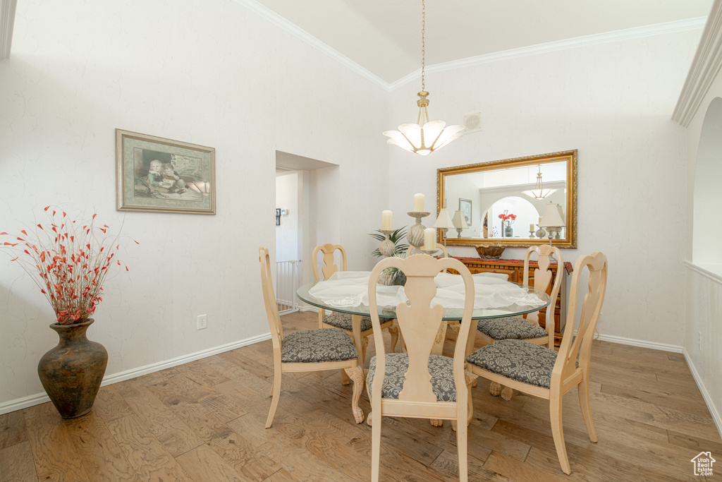 Dining room with high vaulted ceiling, hardwood / wood-style flooring, and crown molding