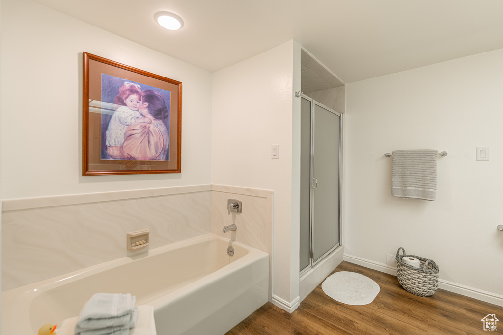 Bathroom featuring shower with separate bathtub and wood-type flooring