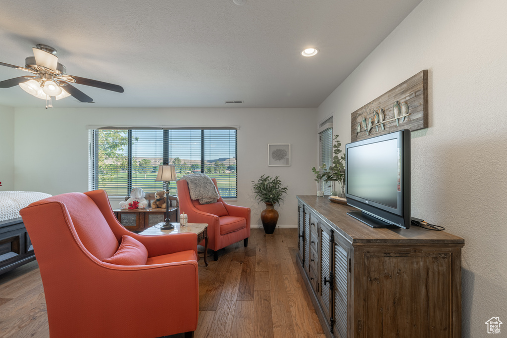 Living room with ceiling fan and hardwood / wood-style floors