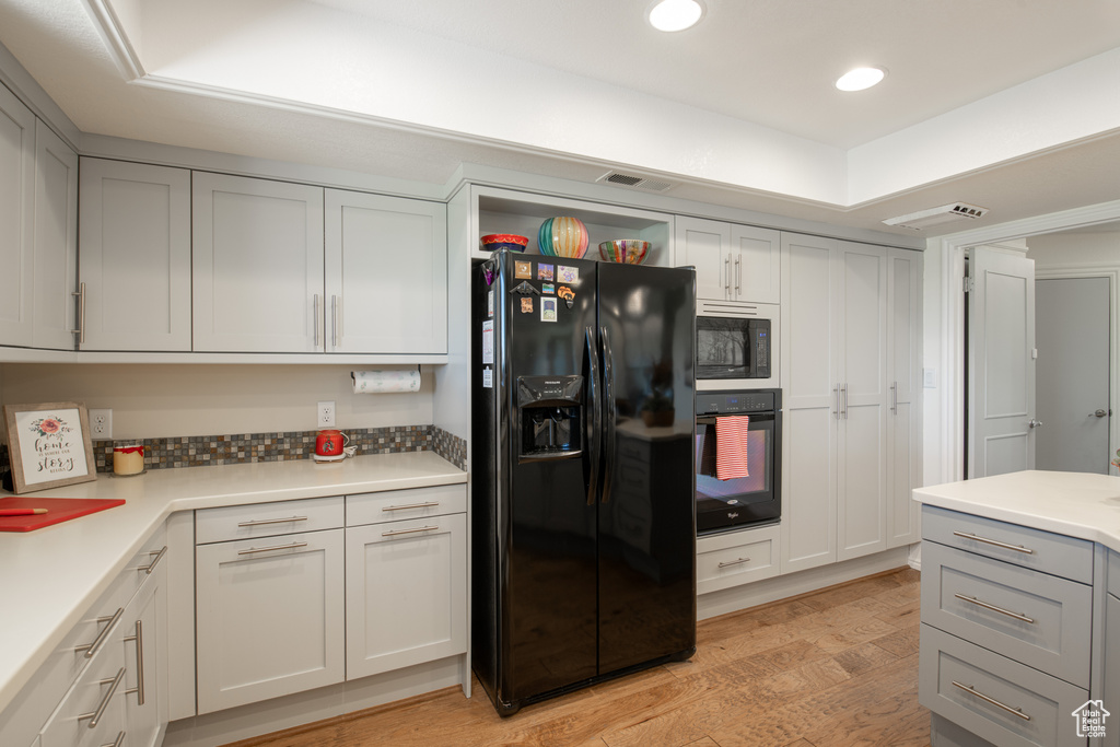 Kitchen with black appliances and light hardwood / wood-style floors