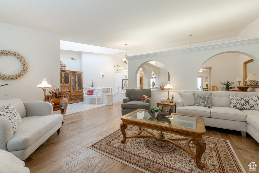 Living room featuring a notable chandelier, crown molding, and hardwood / wood-style floors