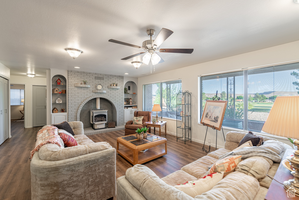 Living room featuring ceiling fan, a fireplace, dark hardwood / wood-style floors, and a wood stove