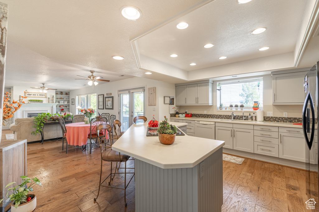 Kitchen with ceiling fan, light wood-type flooring, a kitchen bar, and a healthy amount of sunlight