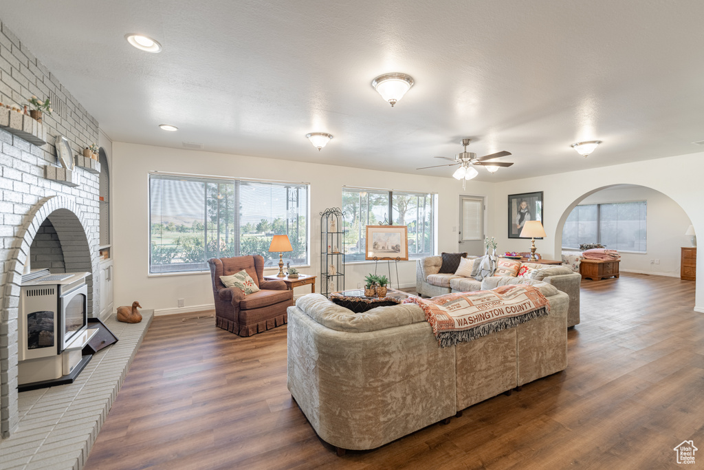 Living room featuring a brick fireplace, hardwood / wood-style flooring, and ceiling fan