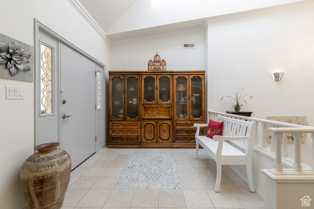 Tiled foyer entrance featuring ornamental molding and high vaulted ceiling