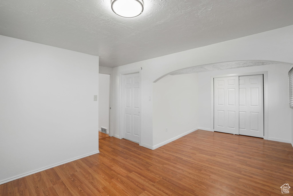 Empty room with a textured ceiling and hardwood / wood-style floors