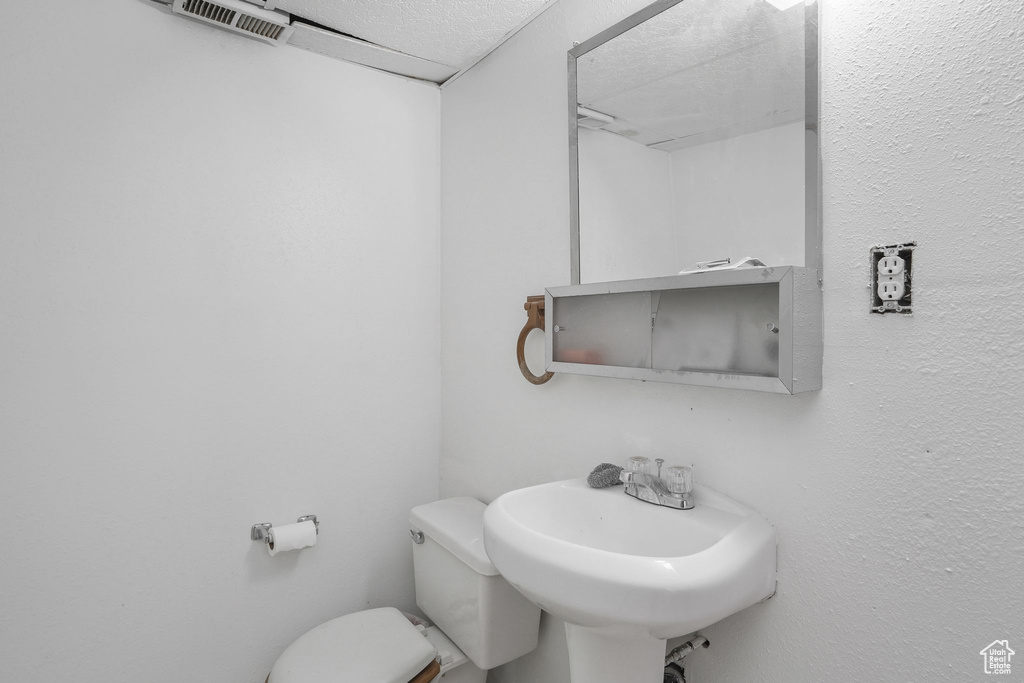 Bathroom featuring a textured ceiling, sink, and toilet