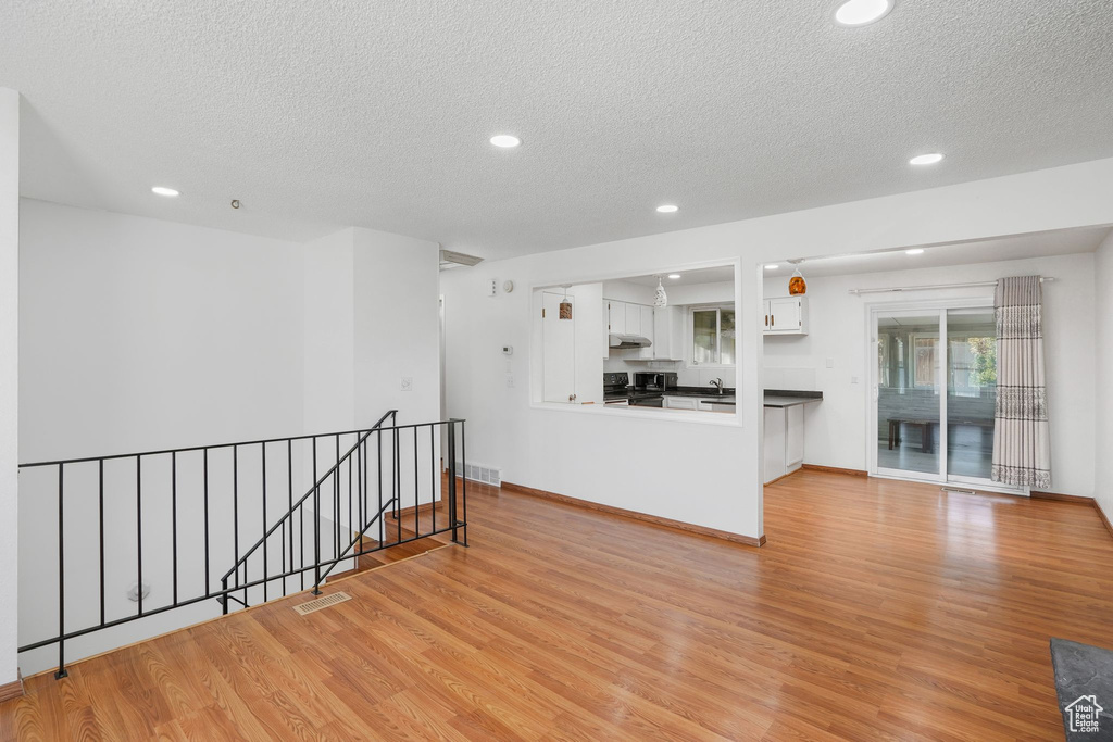 Living room with light wood-type flooring, a textured ceiling, and sink