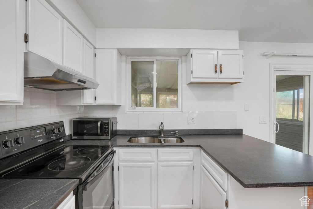 Kitchen with decorative backsplash, white cabinetry, and stainless steel appliances