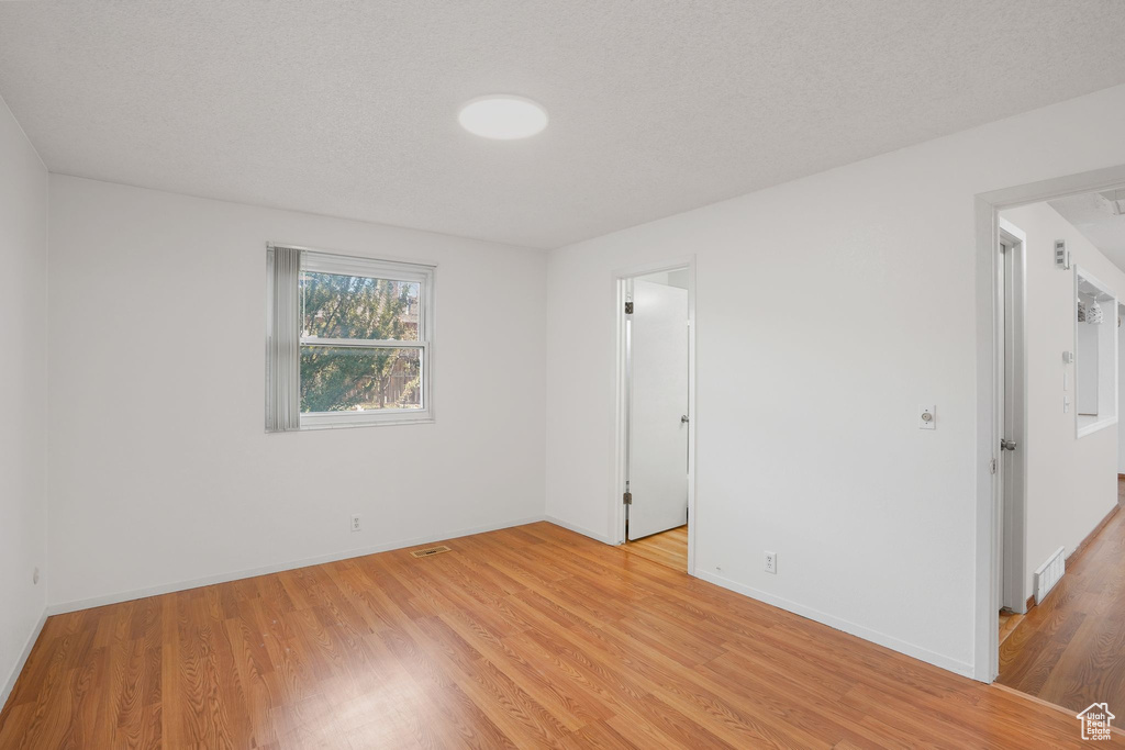 Unfurnished room featuring light hardwood / wood-style floors and a textured ceiling