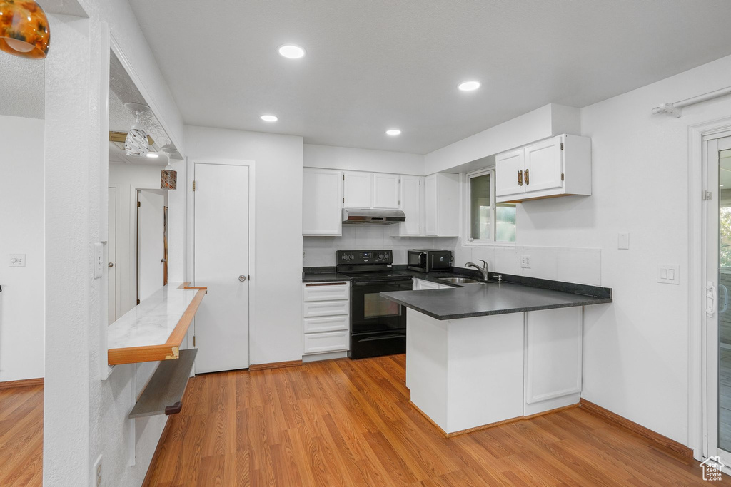 Kitchen featuring light hardwood / wood-style flooring, white cabinetry, electric range, and sink