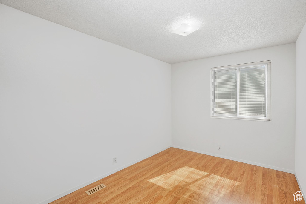 Spare room with a textured ceiling and hardwood / wood-style flooring