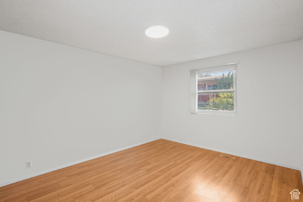 Unfurnished room with a textured ceiling and light hardwood / wood-style flooring