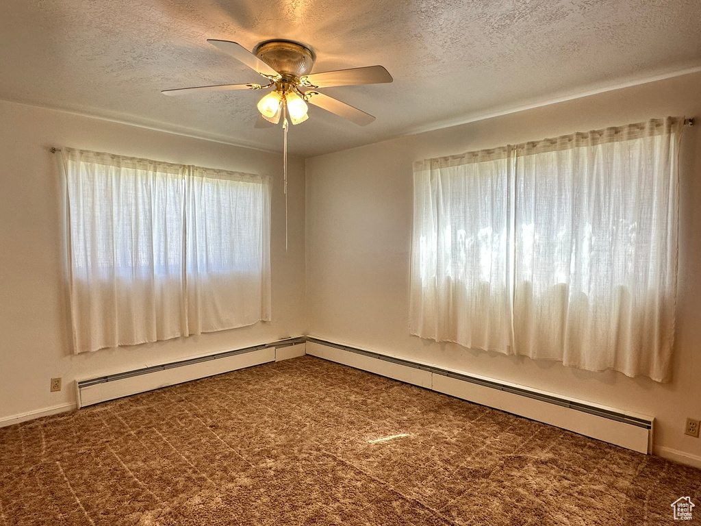 Carpeted empty room featuring ceiling fan and a textured ceiling