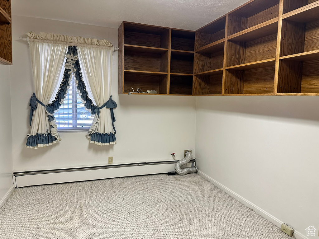 Spacious closet with carpet floors and a baseboard radiator