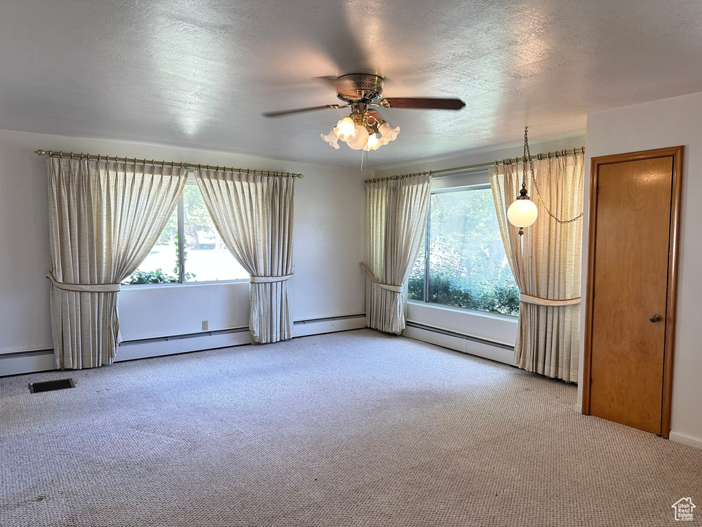 Spare room featuring ceiling fan, a textured ceiling, baseboard heating, and light carpet