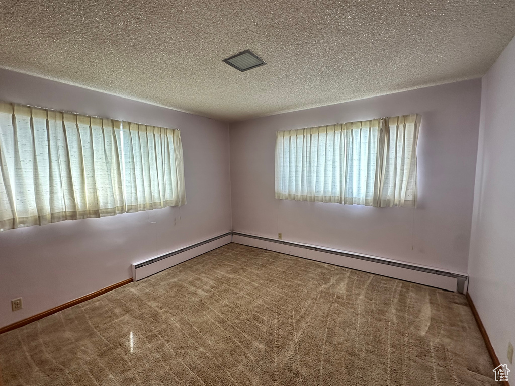 Unfurnished room featuring a textured ceiling, carpet flooring, and baseboard heating