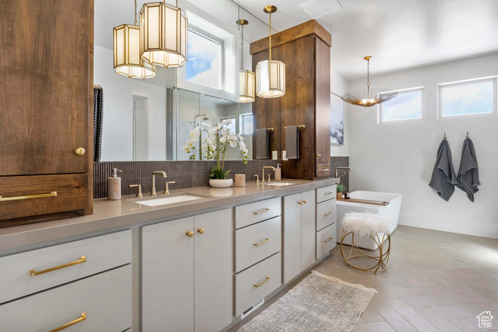 Bathroom with tasteful backsplash, vanity, a bath, and parquet floors