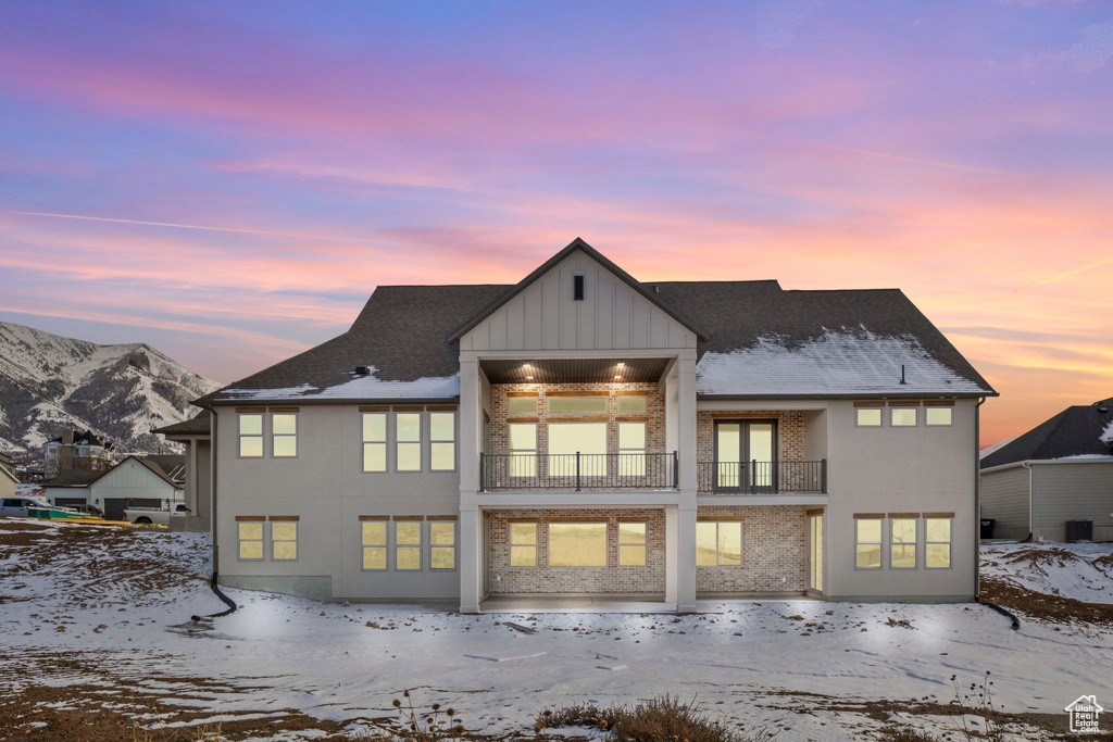 Snow covered house featuring a balcony and a mountain view