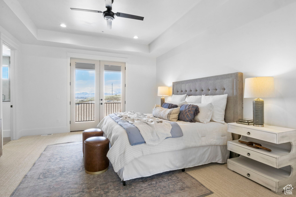 Bedroom featuring a tray ceiling, access to outside, light colored carpet, and french doors