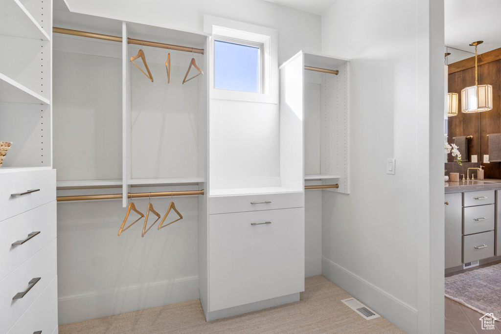 Walk in closet featuring sink and light carpet