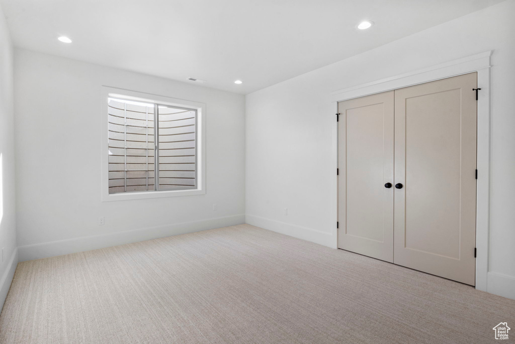 Unfurnished bedroom with light colored carpet and a closet