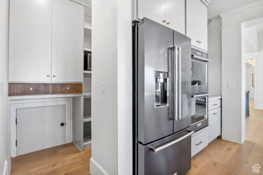 Kitchen with white cabinetry, appliances with stainless steel finishes, and light wood-type flooring