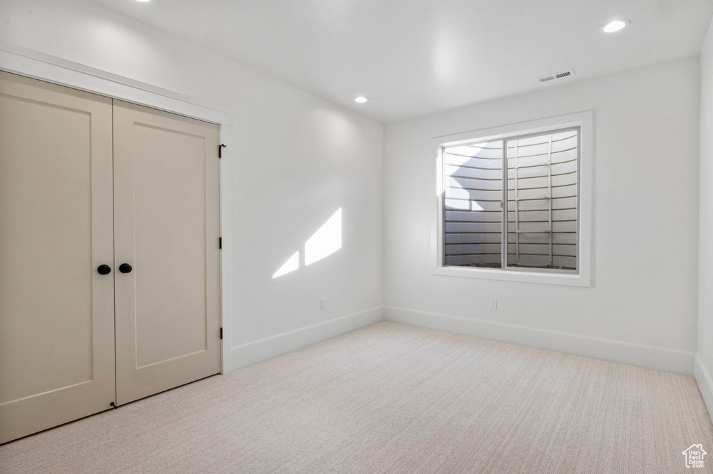 Unfurnished bedroom with light colored carpet and a closet