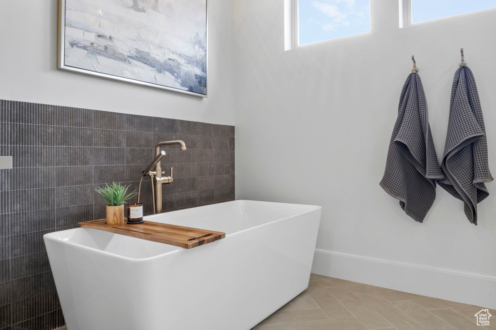 Bathroom featuring tile patterned floors, sink, a bathtub, and tile walls