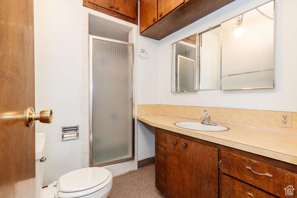 Bathroom with a shower with door, vanity, and toilet