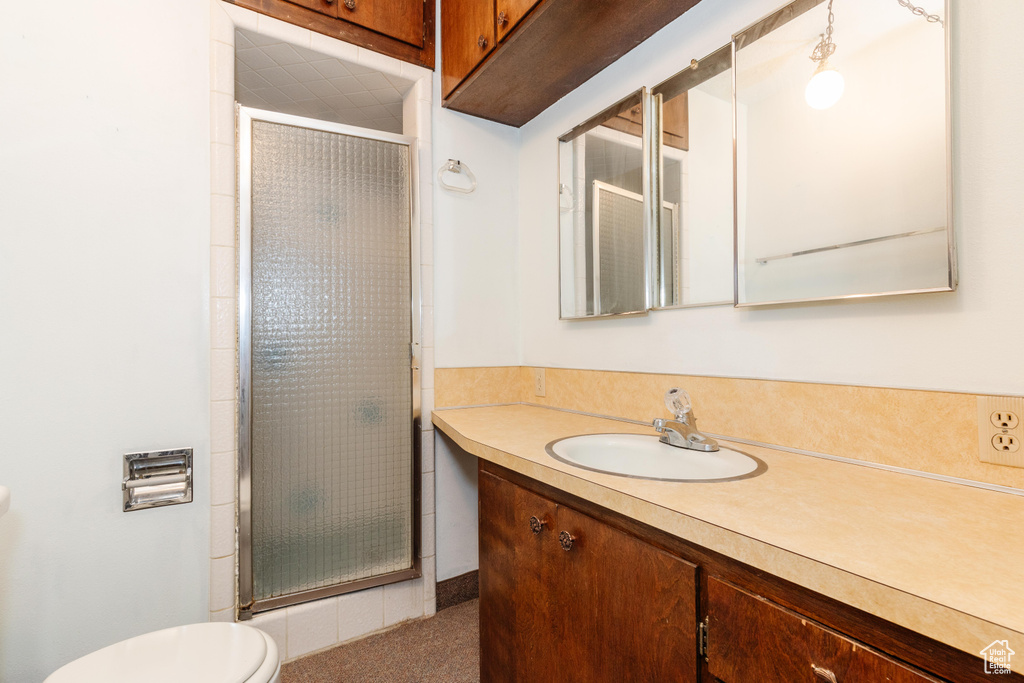 Bathroom featuring a shower with door, vanity, and toilet