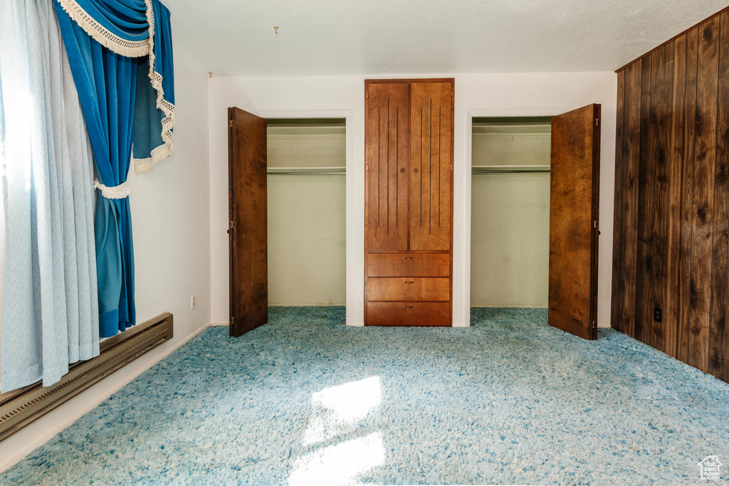 Unfurnished bedroom featuring carpet floors and baseboard heating