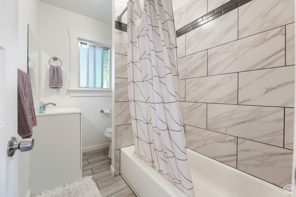 Full bathroom featuring vanity, shower / tub combo, and toilet