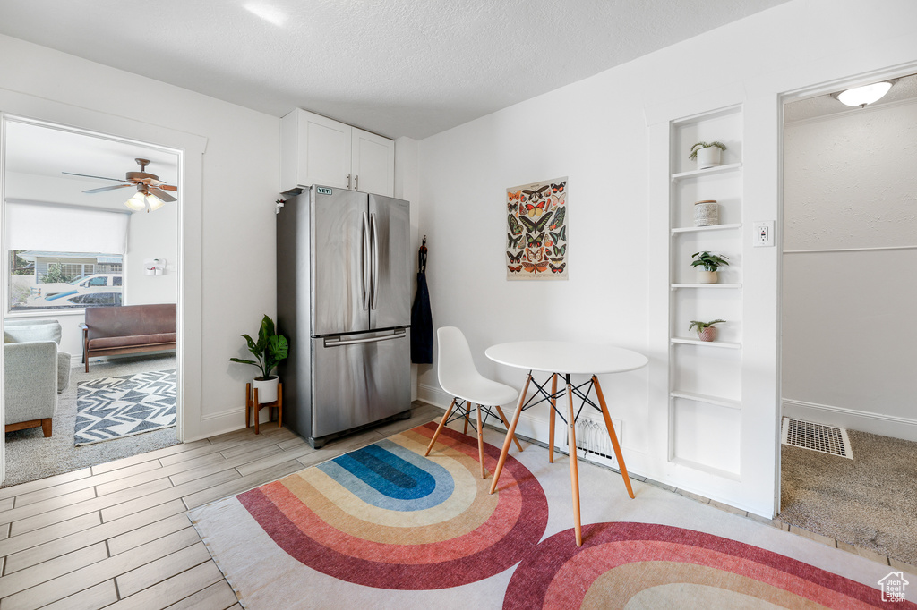 Interior space with ceiling fan, a textured ceiling, light hardwood / wood-style flooring, and built in shelves