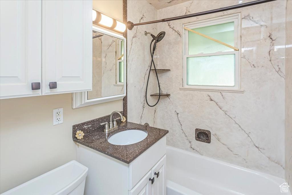 Full bathroom featuring tiled shower / bath combo, vanity, and toilet