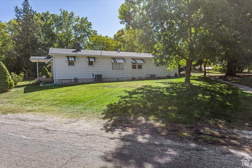 View of front facade featuring cooling unit and a front yard