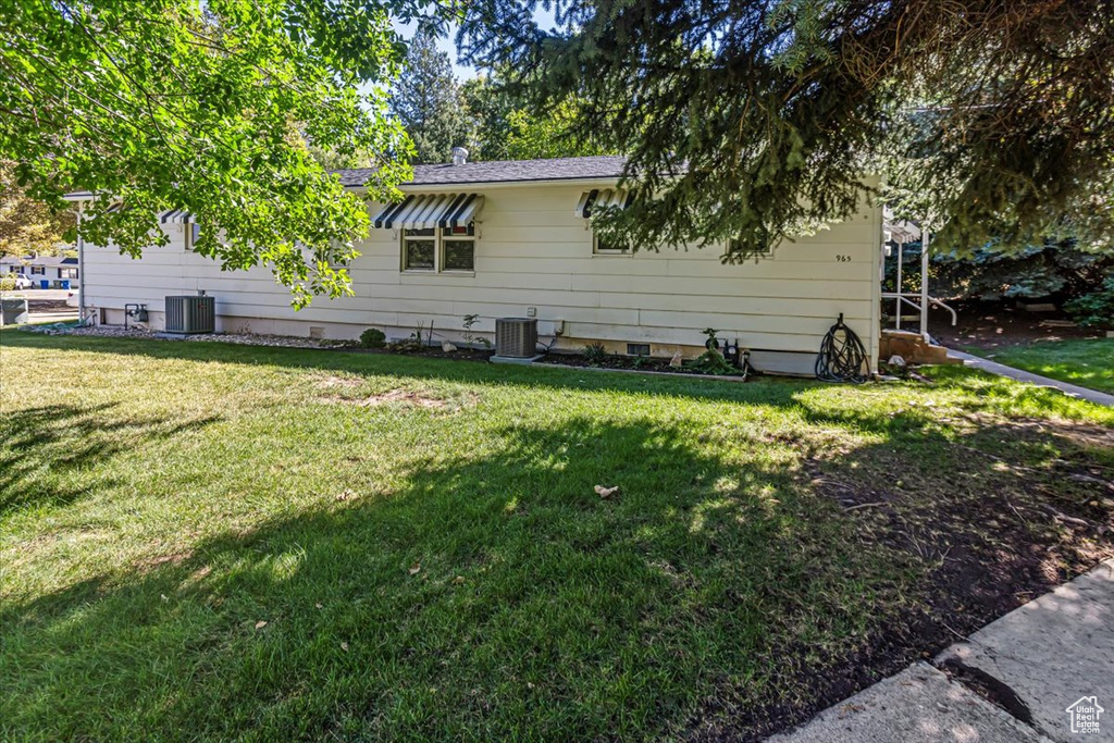 Rear view of property featuring a lawn and central AC unit