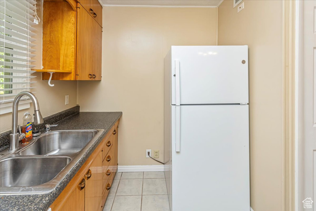 Kitchen featuring light tile patterned flooring, sink, and white fridge