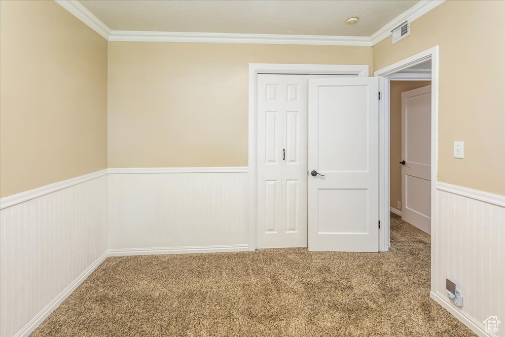 Unfurnished bedroom with carpet floors, a closet, and crown molding