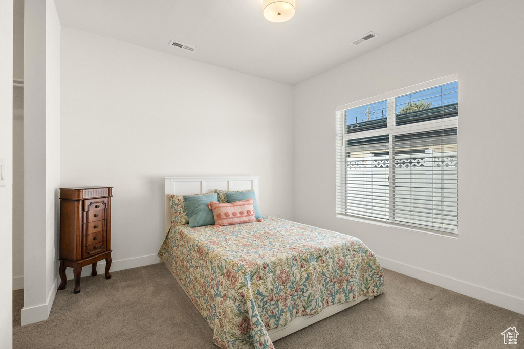 Carpeted bedroom featuring baseboards and visible vents