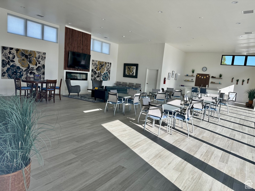 Dining area featuring a towering ceiling, light wood-type flooring, and a healthy amount of sunlight