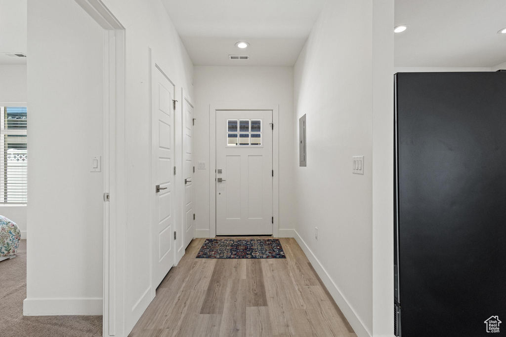 Doorway featuring electric panel, visible vents, baseboards, light wood finished floors, and recessed lighting