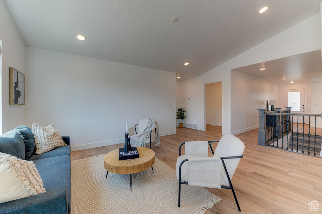 Living room with light wood-type flooring and lofted ceiling