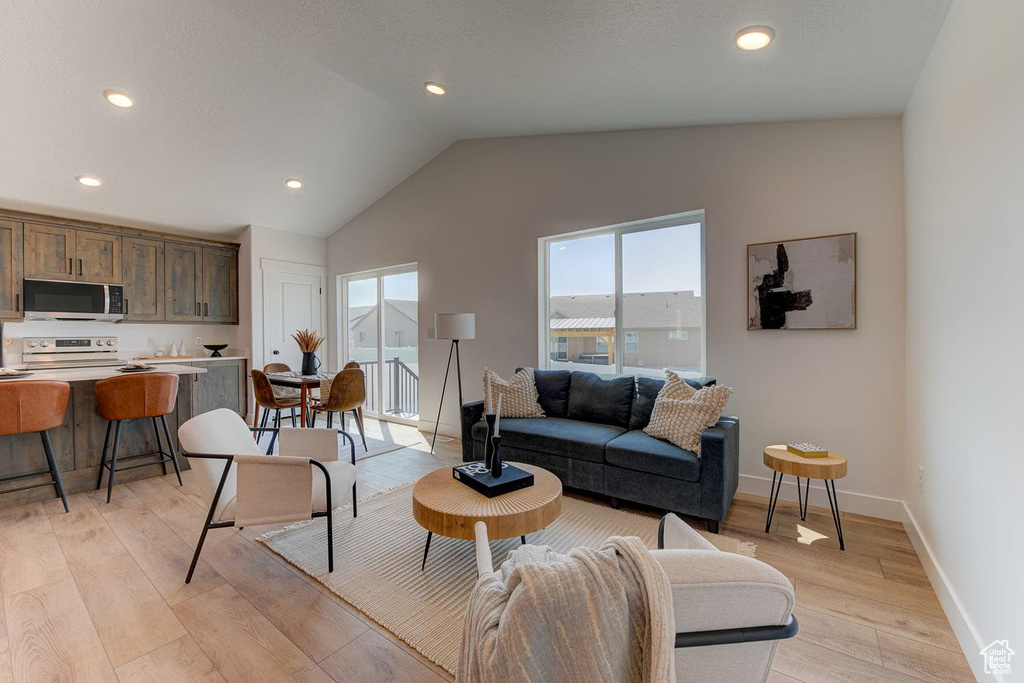 Living room with lofted ceiling and light hardwood / wood-style floors