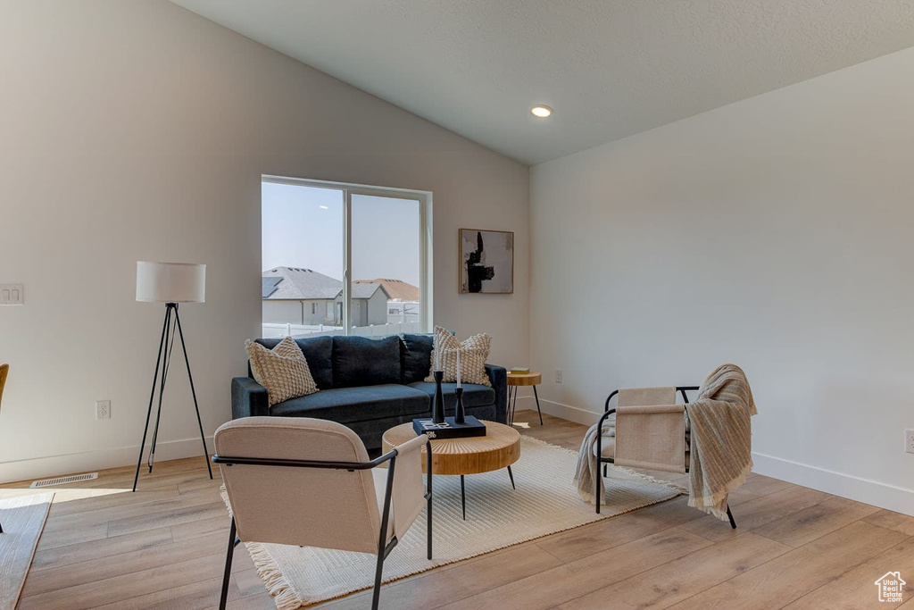 Living room with light wood-type flooring and vaulted ceiling