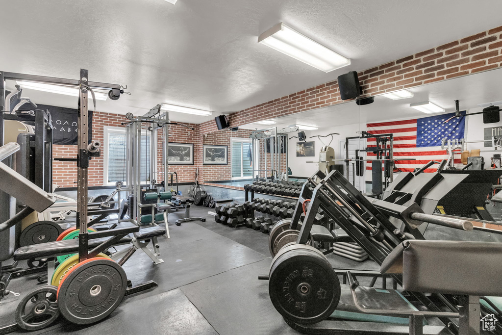 Workout area featuring brick wall and a textured ceiling